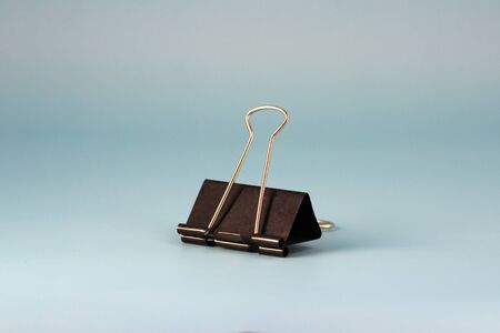 Stationery clip in black lies on a blue background.の写真素材