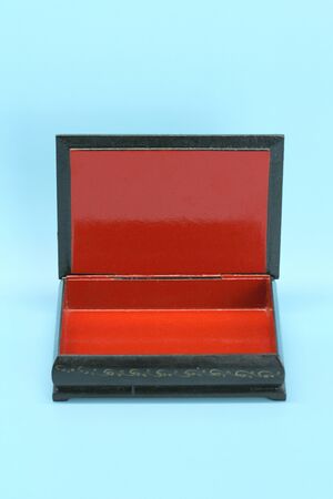 Black with gold painted empty lacquered wooden casket stands open. Inside is red.の写真素材