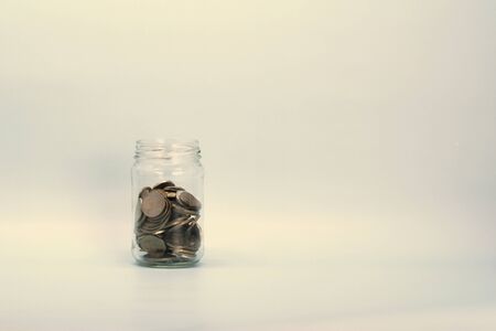 Metal coins, Russian rubles, lie in a transparent glass jar on a light background. Place for text...