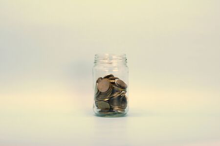 Metal coins, Russian rubles, lie in a transparent glass jar on a light background. Place for text and design.の写真素材