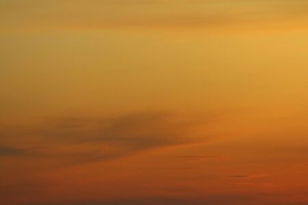 Sun below the horizon and clouds in the fiery dramatic orange sky at sunset or dawn backlit by the sun. Place for text and design.の写真素材