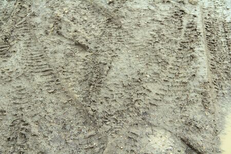 Dirty dirt road with track, wheel marks, brown clay and puddles in Russia.の写真素材
