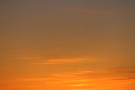 Sun below the horizon and clouds in the fiery dramatic orange sky at sunset or dawn backlit by the sun. Place for text and design.の写真素材