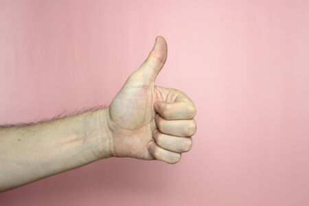 Male hand with fair skin shows a gesture, hand on a light pink background. Stock photo for web and print.の写真素材