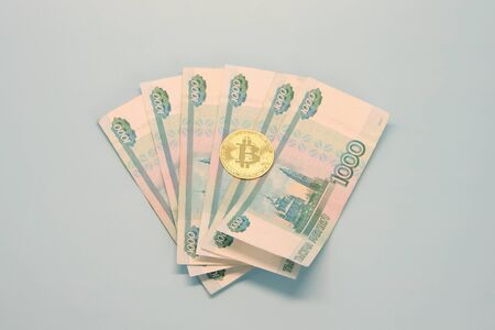 Russian money paper bills of one thousand rubles denominated in a fan. Bitcoin is on top.の写真素材
