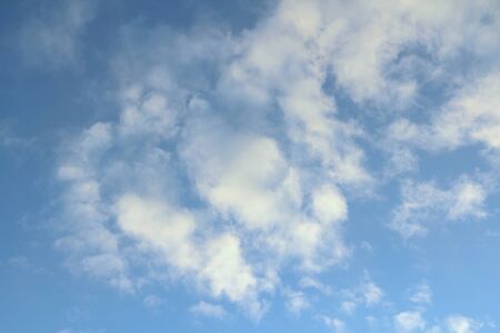 Clouds in the blue sky at sunset or dawn backlit by the sun. Place for text and design.の写真素材