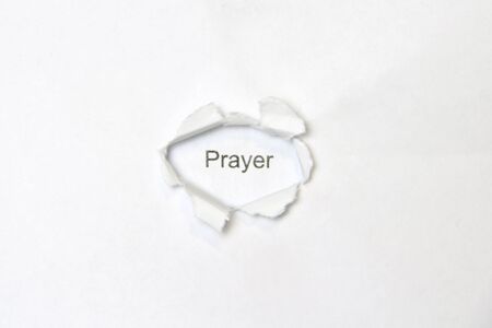 Word prayer on white isolated background, the inscription through the wound hole in the paper. Stock photo for web and print with empty space for text and design.の写真素材