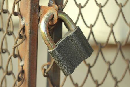 Gray iron shiny padlock hanging on an iron door in the street.の写真素材
