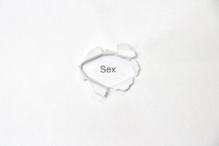 Word sex on white isolated background, the inscription through wound hole in paper. Concept of gender identity and sexual minorities. Stock photo for web and print with empty space for textの写真素材
