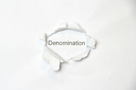 Word denomination on white isolated background, the inscription through the wound hole in the paper. Stock photo for web and print with empty space for text and design.の写真素材