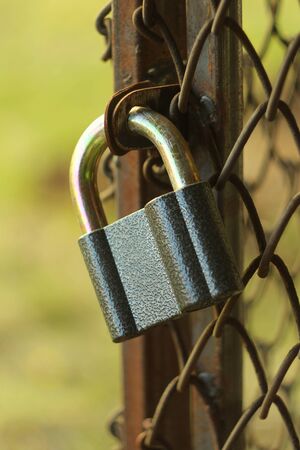 Gray iron shiny padlock hanging on an iron door in the street.の写真素材