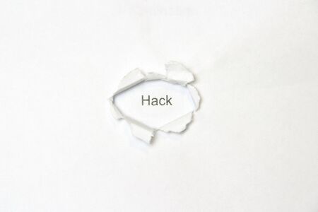 Word hack on white isolated background, the inscription through the wound hole in the paper. Stock photo for web and print with empty space for text and design.の写真素材