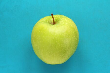 Green yellow apple on a blue background. Juicy ripe beautiful fruit.の写真素材