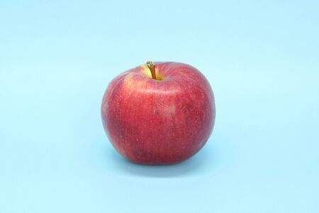 Red yellow apple on a blue background. Juicy ripe beautiful fruit.の写真素材