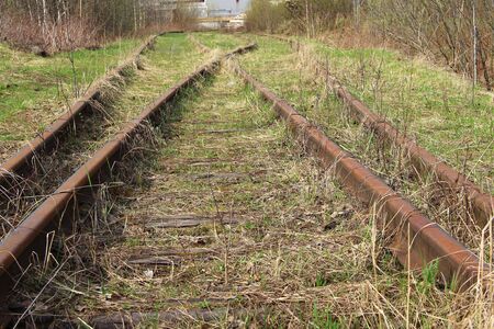 The railway stretching into the distance against the background of young green grass and trees in spring.の写真素材
