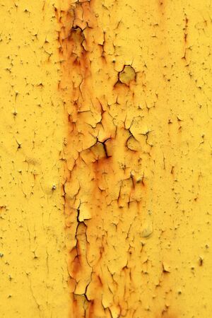 Wall with yellow peeling paint with cracks and rust. Speckles on a painted surface. Aging weathered texture.の写真素材
