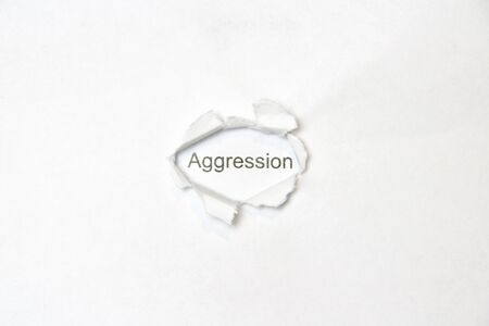 Word aggression on white isolated background, the inscription through the wound hole in the paper. Stock photo for web and print with empty space for text and design.の写真素材