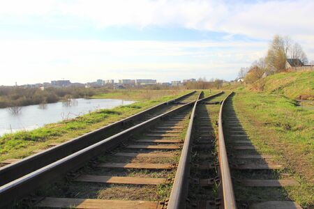 The railway stretching into the distance against the background of young green grass and trees in spring.の写真素材