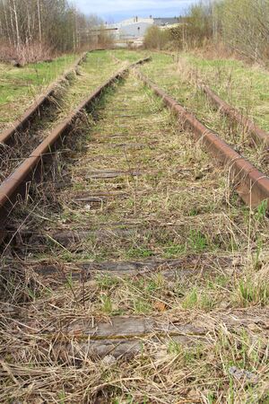 The railway stretching into the distance against the background of young green grass and trees in spring.の写真素材