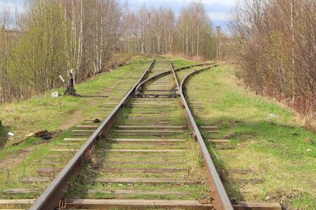 The railway stretching into the distance against the background of young green grass and trees in spring.の写真素材