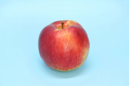 Red yellow apple on a blue background. Juicy ripe beautiful fruit.の写真素材