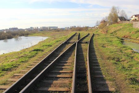 The railway stretching into the distance against the background of young green grass and trees in spring.の写真素材