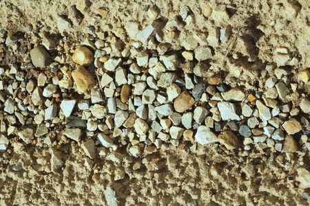Small stones on the sand. The shore of the reservoir of pebbles, rubble. Sea rocky beach. The texture of stone and sand. The background for the design and the place for the text.の写真素材