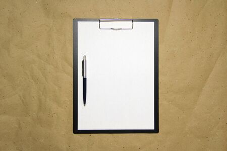 A tablet with a white sheet of A4 format with pen on a beige craft paper. Concept of analysis, study, attentive work. Stock photo with empty place for your text and design.の写真素材
