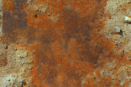 Iron leaf covered with strong deep red and brown rust with sand and stones. The texture of corrosion, wear and destruction. Place for text and background for design.の写真素材
