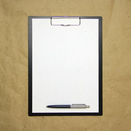 A tablet with a white sheet of A4 format with pen on a beige craft paper. Concept of analysis, study, attentive work. Stock photo with empty place for your text and design.の写真素材