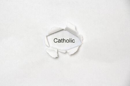 Word catholic on white isolated background, the inscription through the wound hole in paper. Concept of gender identity and sexual minorities. Stock photo for web and print with empty space for textの写真素材