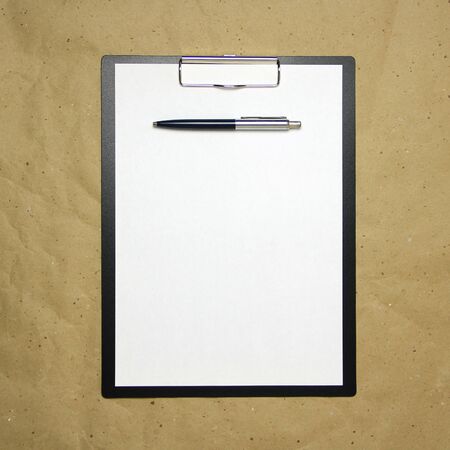 A tablet with a white sheet of A4 format with pen on a beige craft paper. Concept of analysis, study, attentive work. Stock photo with empty place for your text and design.の写真素材