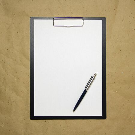 A tablet with a white sheet of A4 format with pen on a beige craft paper. Concept of analysis, study, attentive work. Stock photo with empty place for your text and design.の写真素材