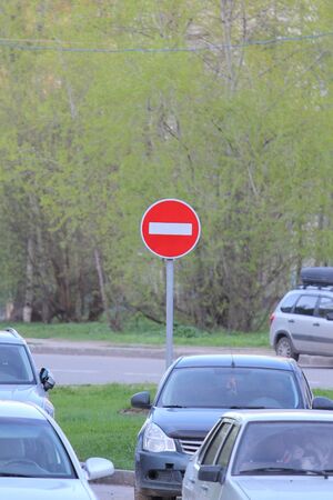 Red round road sign with white stripe prohibiting movement on a city street with cars. Do not enter. concept of prohibition, dead end, hopelessness and stop.の写真素材