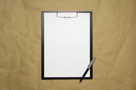 A tablet with a white sheet of A4 format with pen on a beige craft paper. Concept of analysis, study, attentive work. Stock photo with empty place for your text and design.の写真素材
