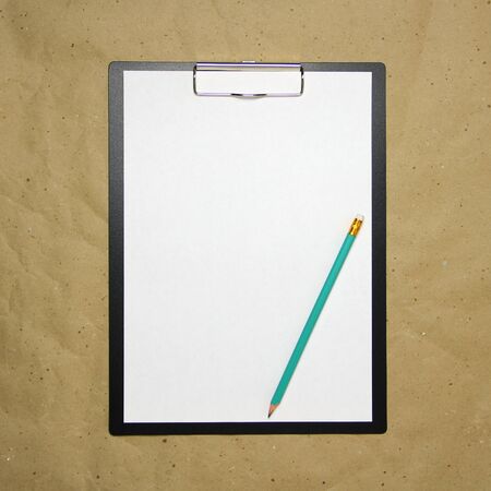 A tablet with a white sheet of A4 format with pencil on a beige craft paper. Concept of new opportunities, ideas, undertakings, innovations. Stock photo with empty place for your text and design.の写真素材