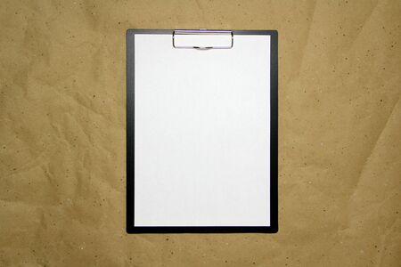 A tablet with a white sheet of A4 format on a beige craft paper. Concept of new opportunities, ideas, undertakings, innovations. Stock photo with empty place for your text and design.の写真素材