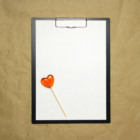 The tablet with a clip for the clip of paper with a white sheet a4 lies against the background of craft brown crumpled paper. Place for text and layout for design.の写真素材