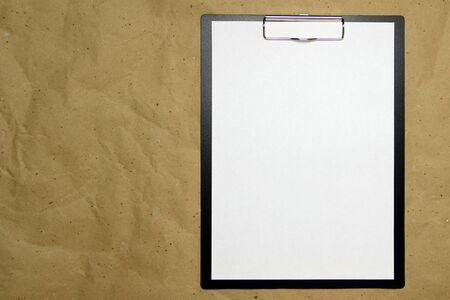 A tablet with a white sheet of A4 format on a beige craft paper. Concept of new opportunities, ideas, undertakings, innovations. Stock photo with empty place for your text and design.の写真素材