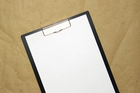 A tablet with a white sheet of A4 format on a beige craft paper. Concept of new opportunities, ideas, undertakings, innovations. Stock photo with empty place for your text and design.の写真素材