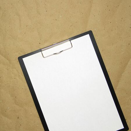 A tablet with a white sheet of A4 format on a beige craft paper. Concept of new opportunities, ideas, undertakings, innovations. Stock photo with empty place for your text and design.の写真素材