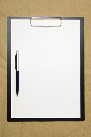 A tablet with a white sheet of A4 format with pen on a beige craft paper. Concept of analysis, study, attentive work. Stock photo with empty place for your text and design.の写真素材