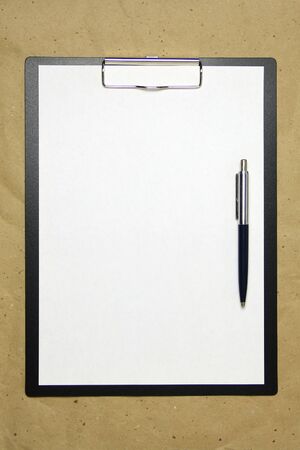 A tablet with a white sheet of A4 format with pen on a beige craft paper. Concept of analysis, study, attentive work. Stock photo with empty place for your text and design.の写真素材