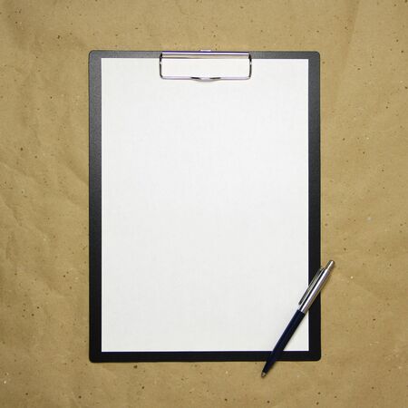 A tablet with a white sheet of A4 format with pen on a beige craft paper. Concept of analysis, study, attentive work. Stock photo with empty place for your text and design.の写真素材