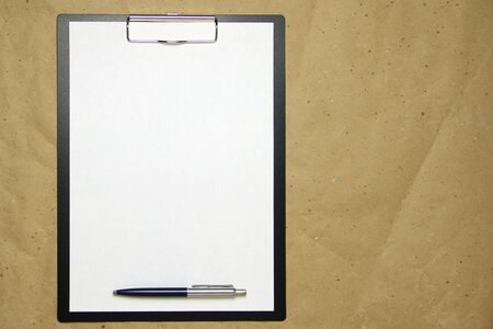 A tablet with a white sheet of A4 format with pen on a beige craft paper. Concept of analysis,...