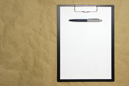 A tablet with a white sheet of A4 format with pen on a beige craft paper. Concept of analysis,...