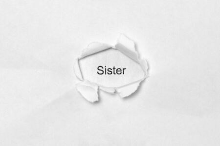 Word Sister on white isolated background, the inscription through the wound hole in paper. Stock photo for web and print with empty space for textの写真素材
