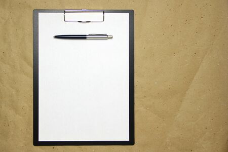 A tablet with a white sheet of A4 format with pen on a beige craft paper. Concept of analysis, study, attentive work. Stock photo with empty place for your text and design.の写真素材