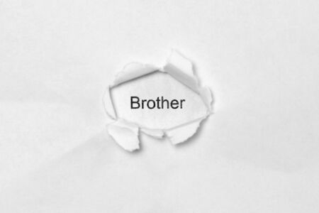 Word Brother on white isolated background, the inscription through the wound hole in paper. Stock photo for web and print with empty space for textの写真素材
