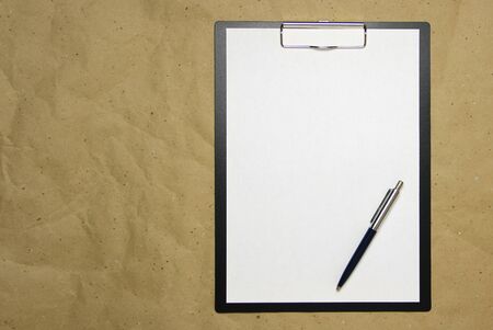 A tablet with a white sheet of A4 format with pen on a beige craft paper. Concept of analysis, study, attentive work. Stock photo with empty place for your text and design.の写真素材